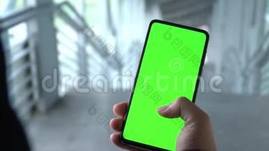 绿色屏幕智能手机。 一个男人`手拿着电话。 在手机的绿色屏幕上滚动。 智能手机录像。